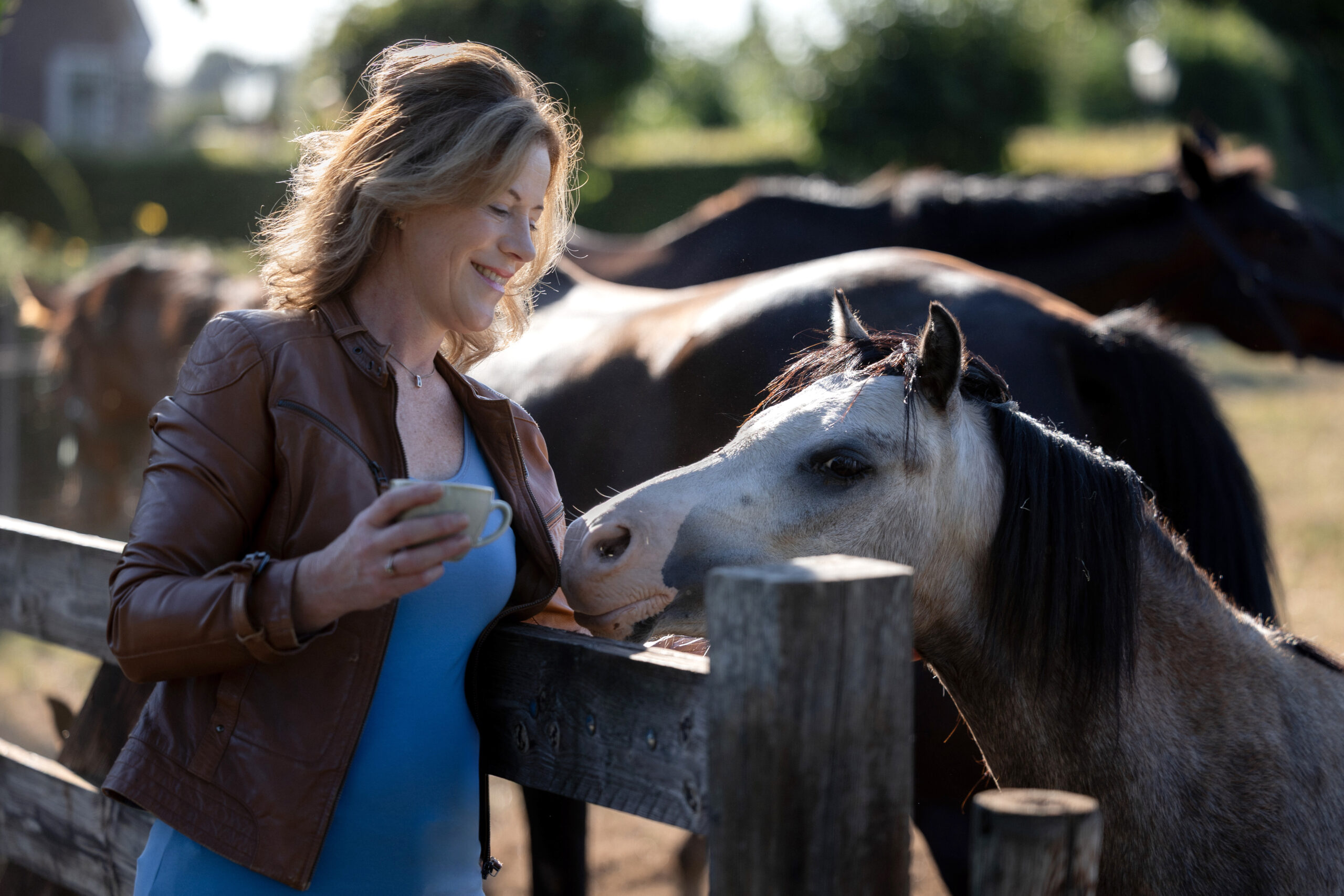 Willeke enjoying a coffee beside a pony at the farm