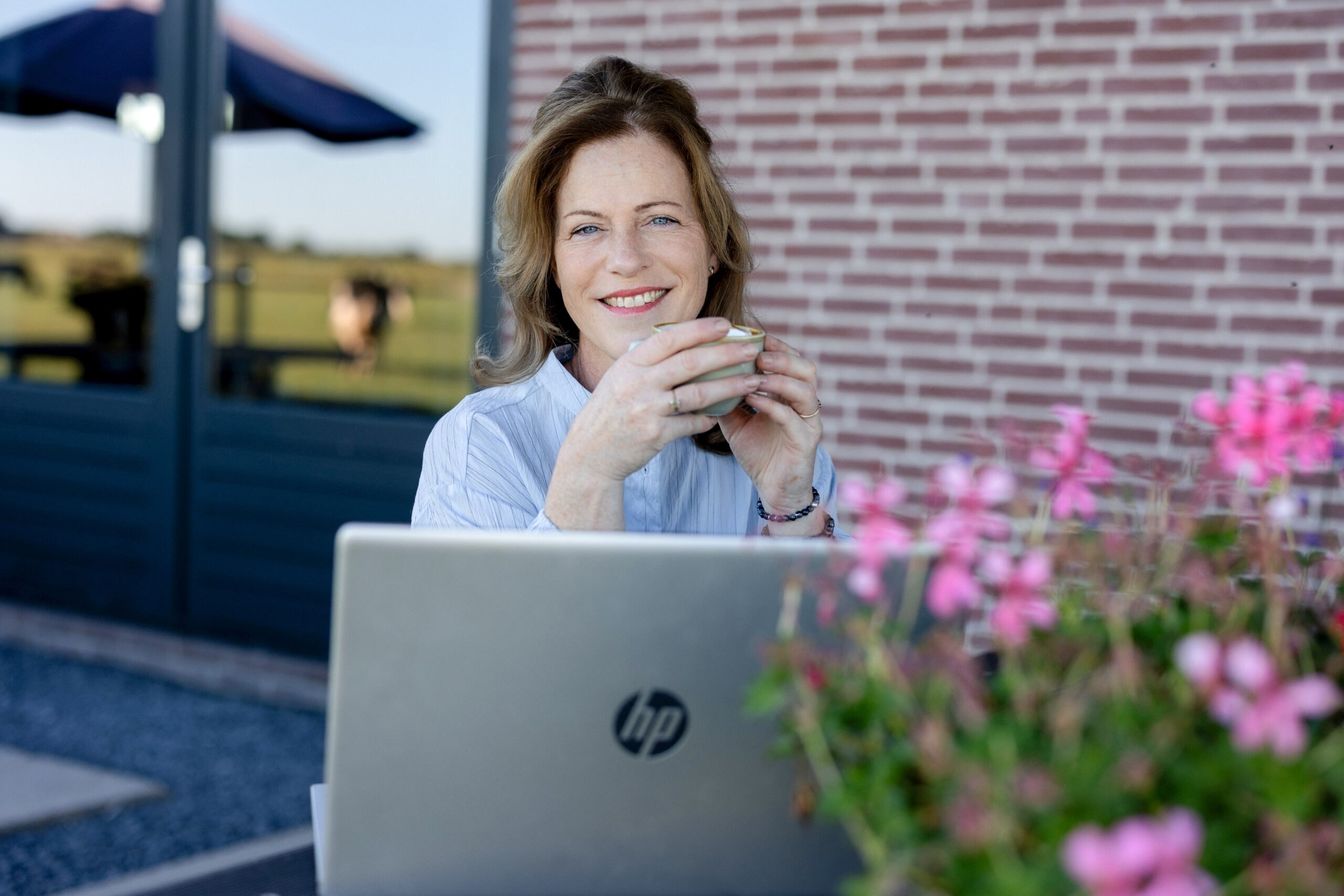 Smiling Willeke with her laptop outdoors at Milk & Meetings